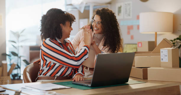 Two business owners celebrating a successful online launch at a laptop